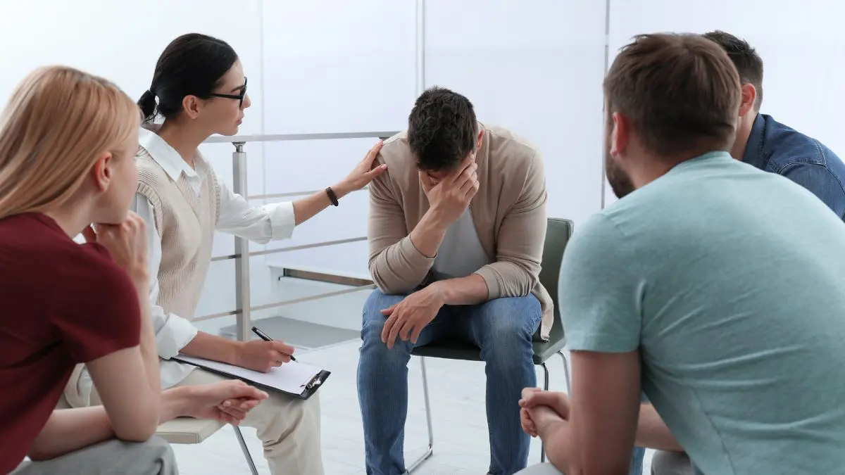 A man struggling with substance abuse receives support from his family during therapy.