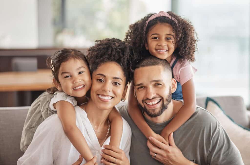 smiling family sits together on couch
