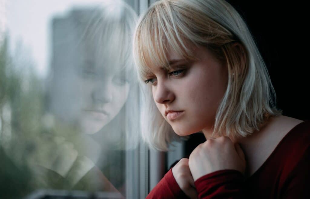 young woman with a drug addiction sits alone by a window