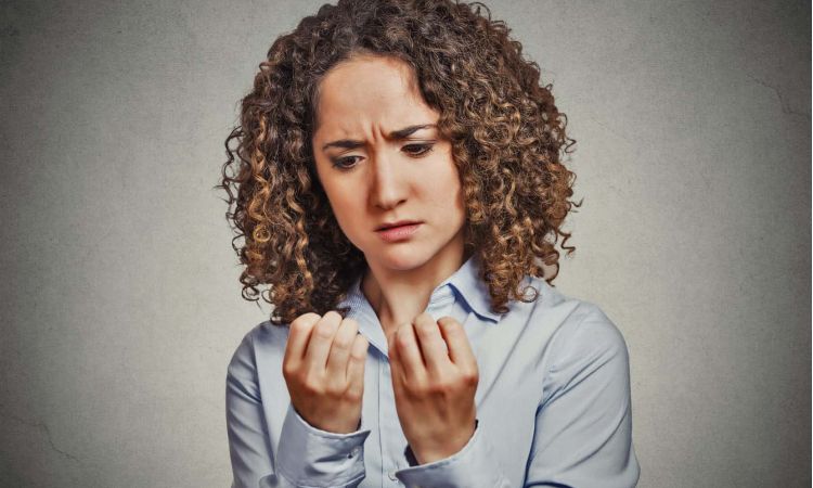 anxious woman looks obsessively at her fingernails